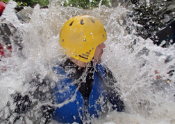 Man sliding down a water chute whilst Canyoning on a stag party