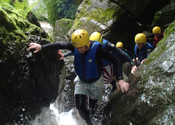 Stag Group climbing up a rock whilst Canyoning
