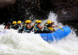 group White water rafting hitting frothing water whilst on a stag weekend