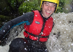 Man sliding down a water chute whilst Canyoning on a stag weekend