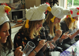 A Hen Party with humorous hats painting glasses in a craft hen activity