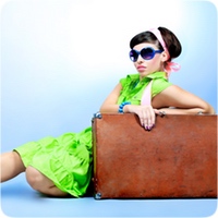 lady in a bright green dress leaning on her suitcase