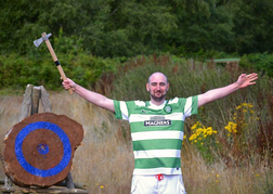 A Man Holding A Ax In The Air Whilst Axe Throwing