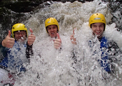 3 Men standing under a small waterfall as part of a stag weekend