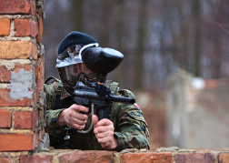 stag party playing Paintball red brick wall for cover