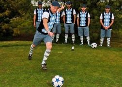 A Stag Party all dressed the same with a guy kicking off at foot golf